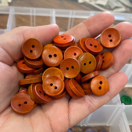 Hand holding orange buttons with a background of button containers.
