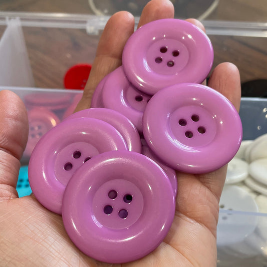 Hand holding pink buttons with a blurred background