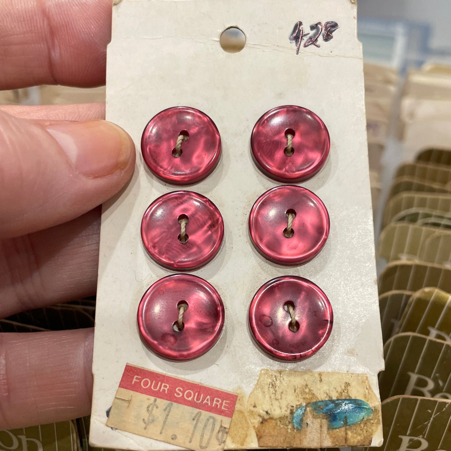 Set of pink buttons on a card held by a hand with a blurred background