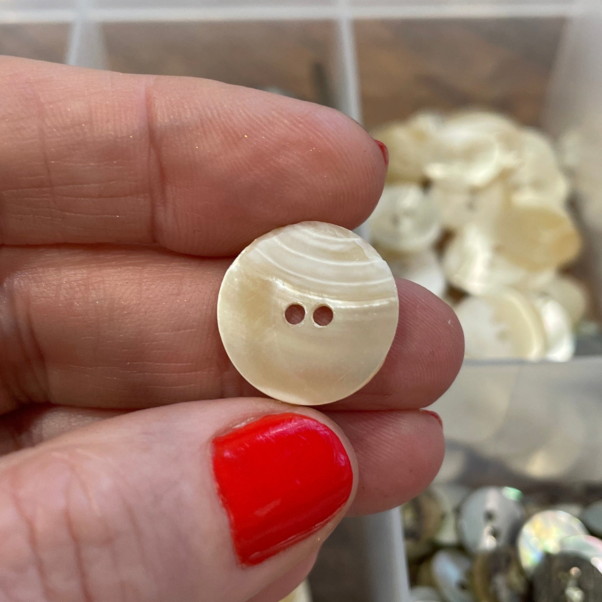 Hand holding a button with a blurred background of button assortment