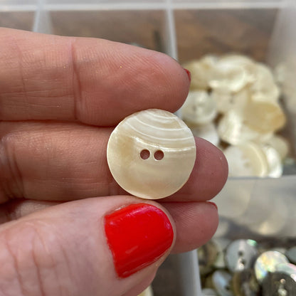Hand holding a button with a blurred background of button assortment