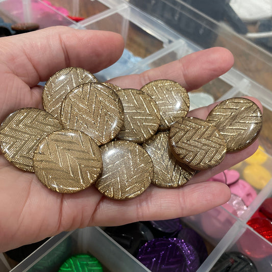 Hand holding gold buttons with a container of colorful buttons in the background