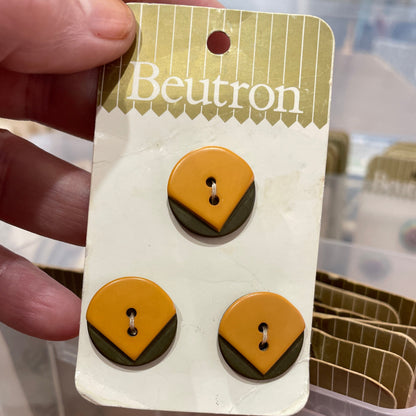 Pair of buttons on a branded card held by a hand.