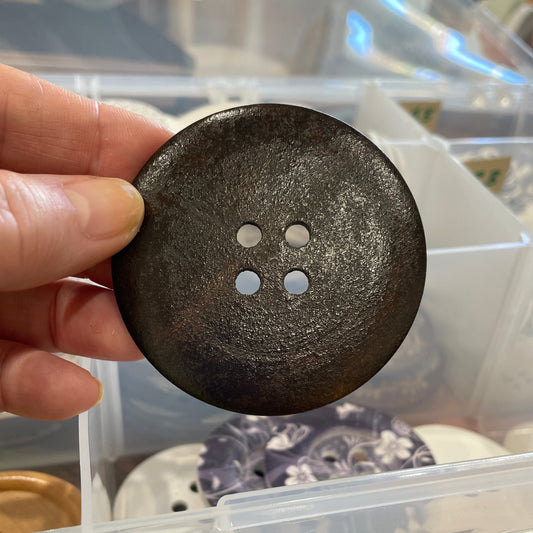 Black button held in front of a clear plastic container