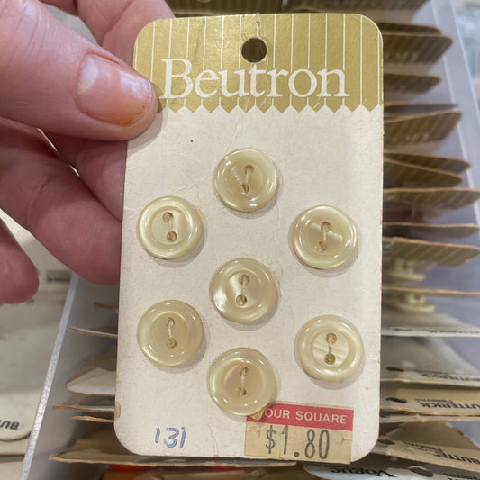 Card with gold buttons held by a hand in front of a display of similar cards.